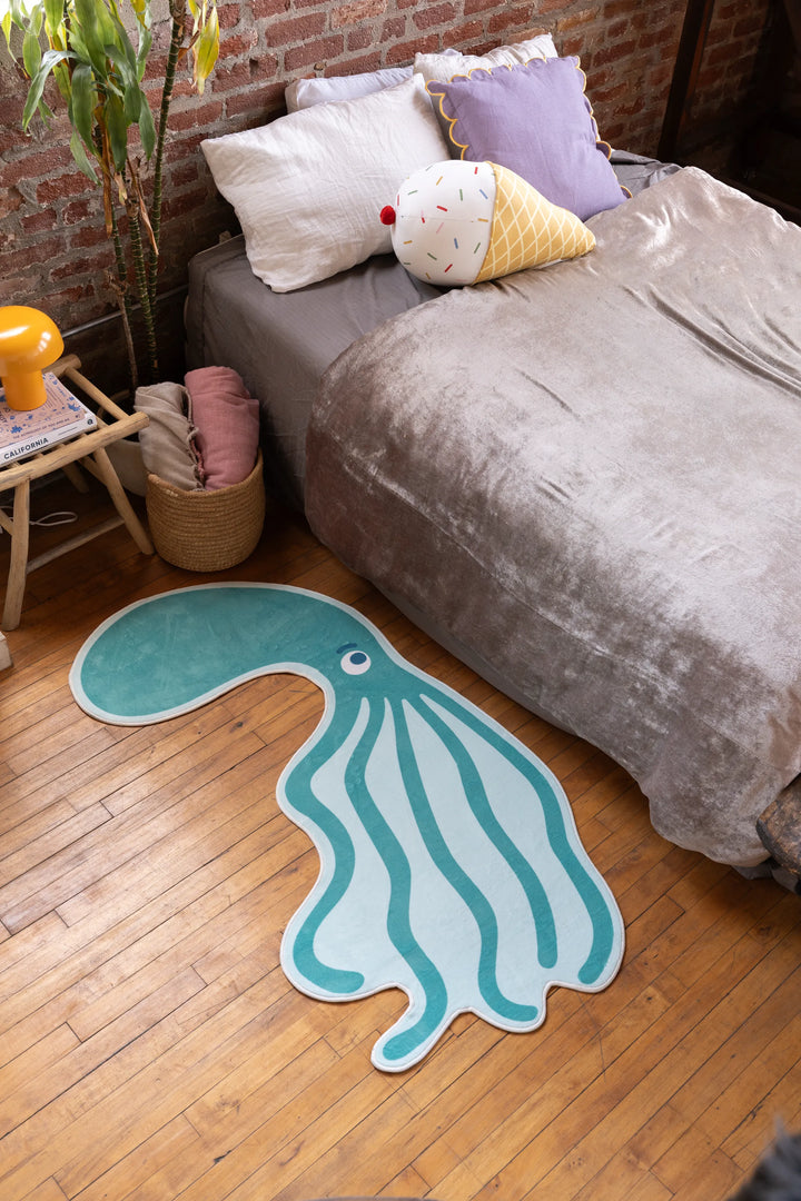 Green octopus-shaped bedroom rug on hardwood floor near bed and nightstand