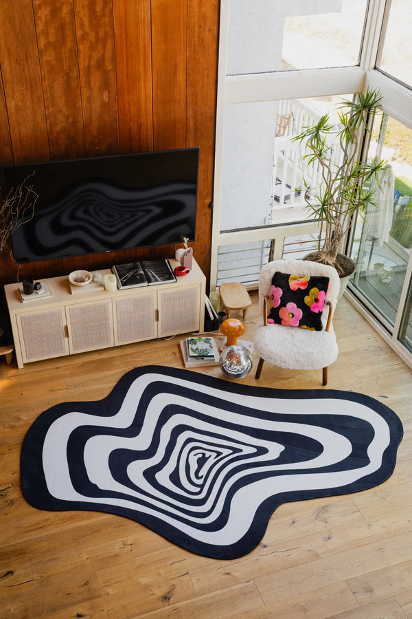 Living room scene featuring the black and white vertigo rug near a TV setup with wooden floors and modern decor.