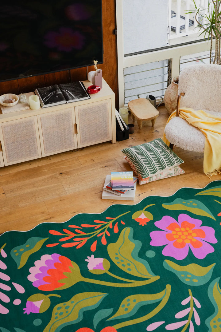 The wavy-edged green rug, accented with pink florals, brings a fresh touch to the living room