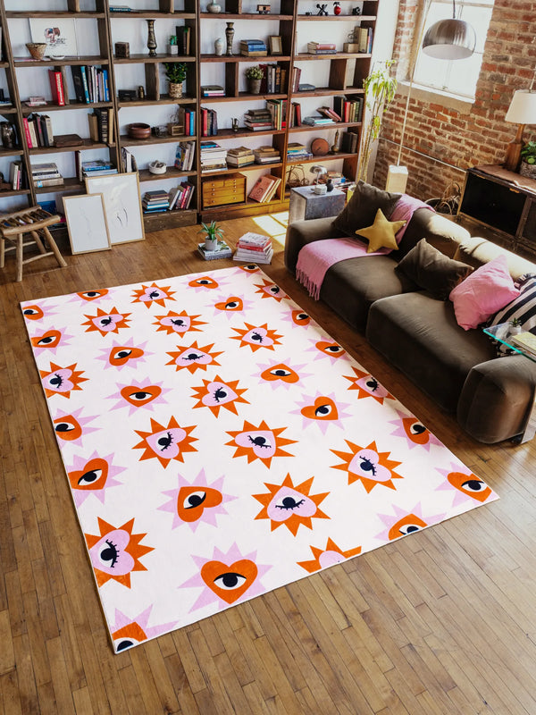 Living room with a colorful patterned rug on wooden floor, brown sofa, and bookshelves.