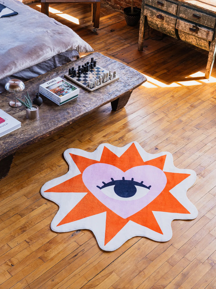 A playful heart eye rug catching sunlight near a bed and rustic bench
