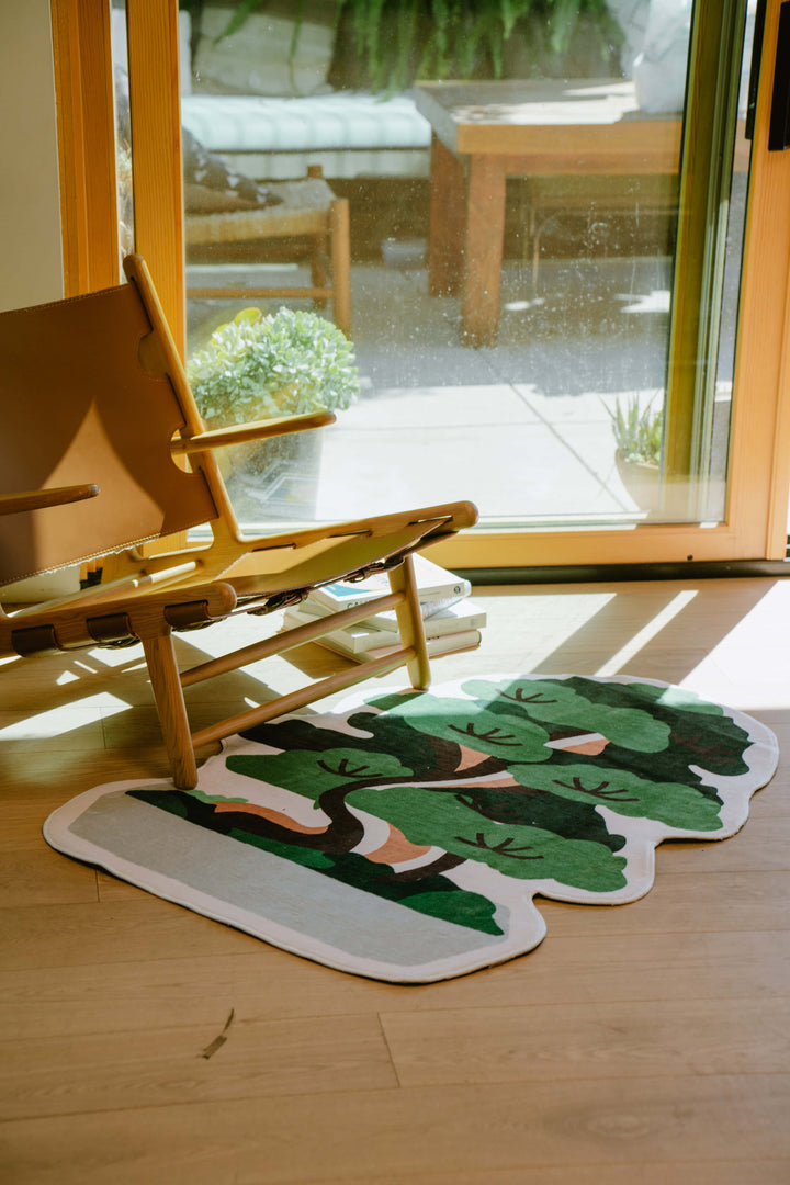 Irregular Shaped Potted Tree Runner Rug by Tuya, styled next to a wooden lounge chair by the patio door.