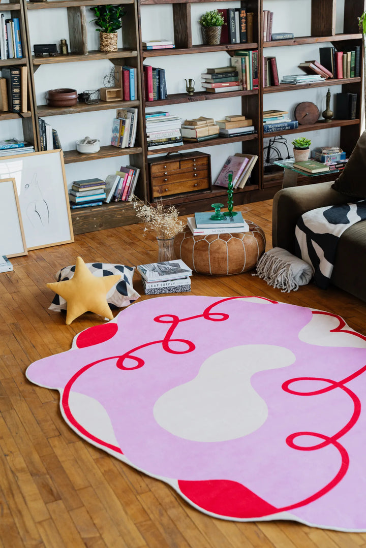 Funky abstract area rug in pink and cream, adding a lively pop near a cozy sofa with textured throws and decor.