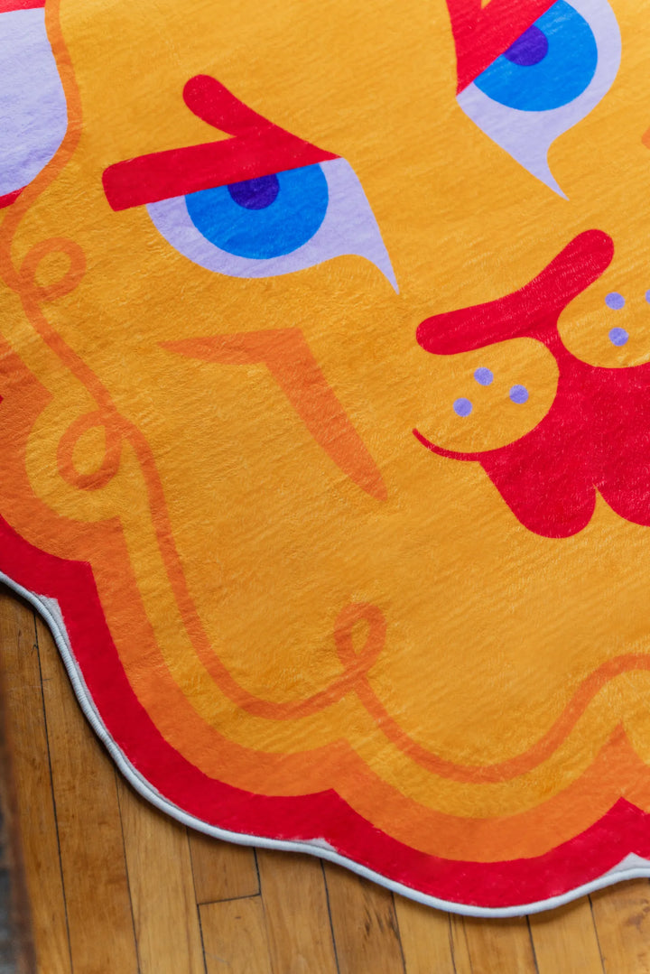 Detail view of cartoon lion head  shaped irregular rug on wood floor.