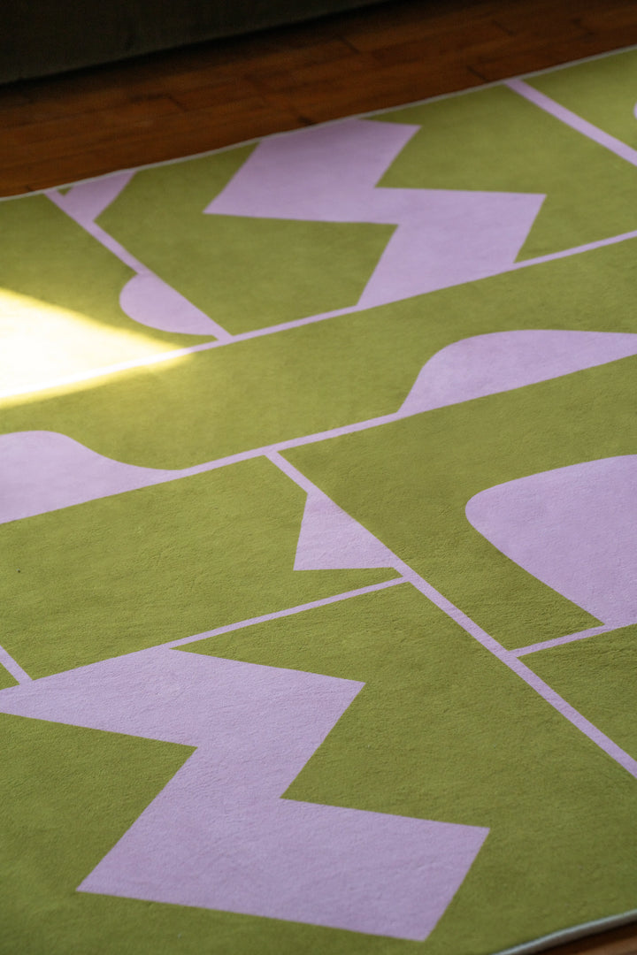 Detail view of Abstract Patchwork Rug in olive green showing playful geometric design in natural lighting