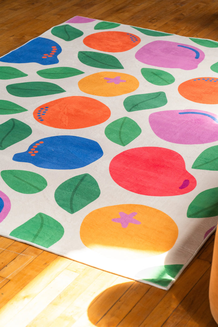Bright pastel rug by Becca Franks laid on wood floor, catching light in a minimal, open space