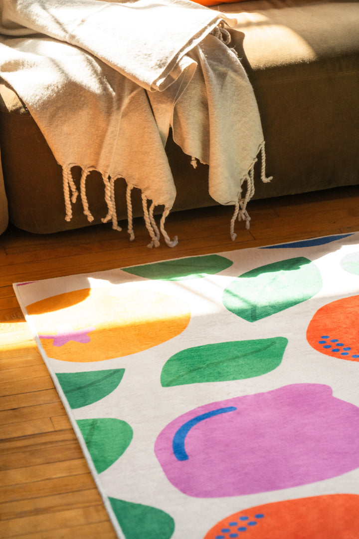Pastel fruit party rug placed near a cozy seating area, catching natural light on the wood floor