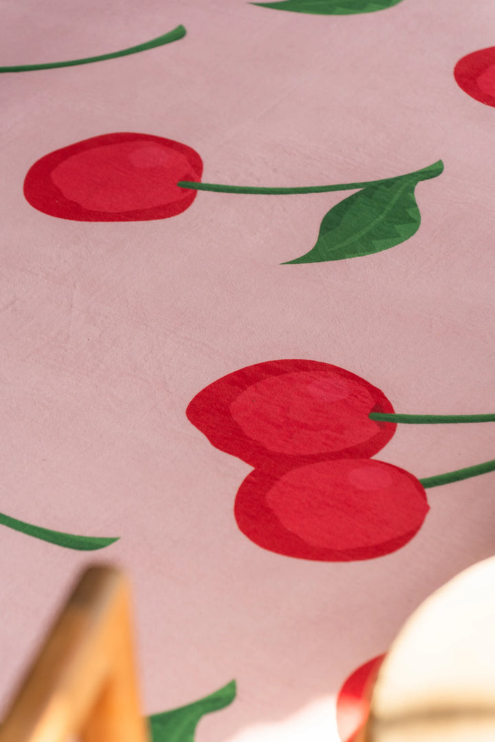Close-up of red cherry illustrations on a pastel pink cute rug, showing soft texture and playful design for modern interiors