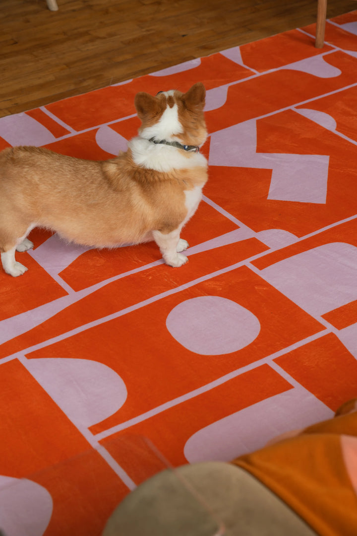 A corgi standing on the Orange Geometric Patchwork Rug, bringing a playful moment to this wood-floored seating nook