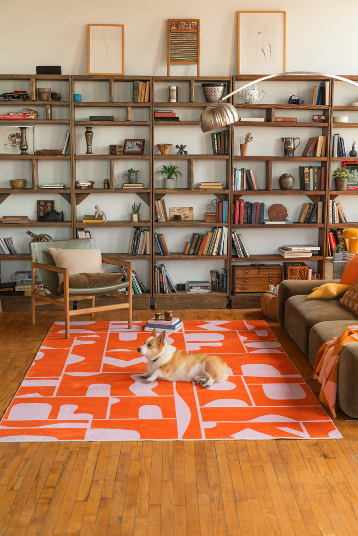 Orange Geometric Patchwork Rug laid out in front of a full-height bookshelf and deep-toned sofa in a soft, natural-lit space