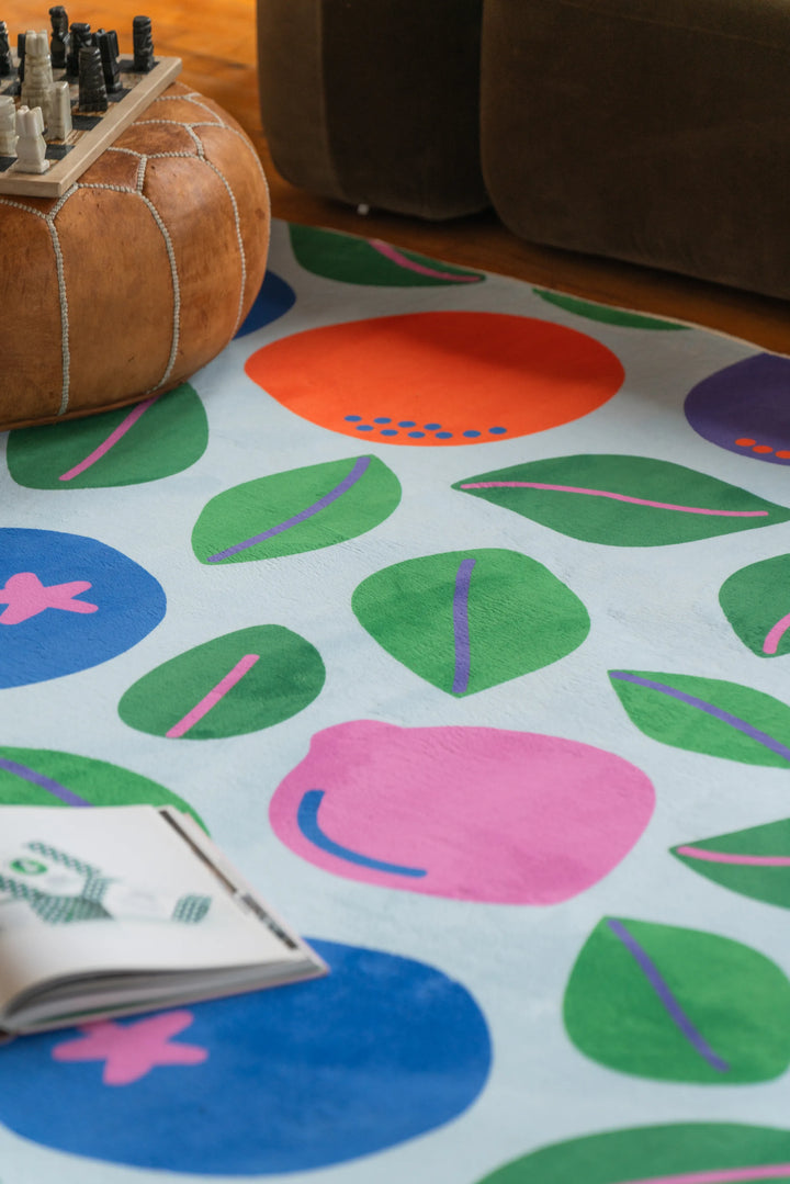 Playful rug featuring bold fruits partially visible under seating in a cozy corner