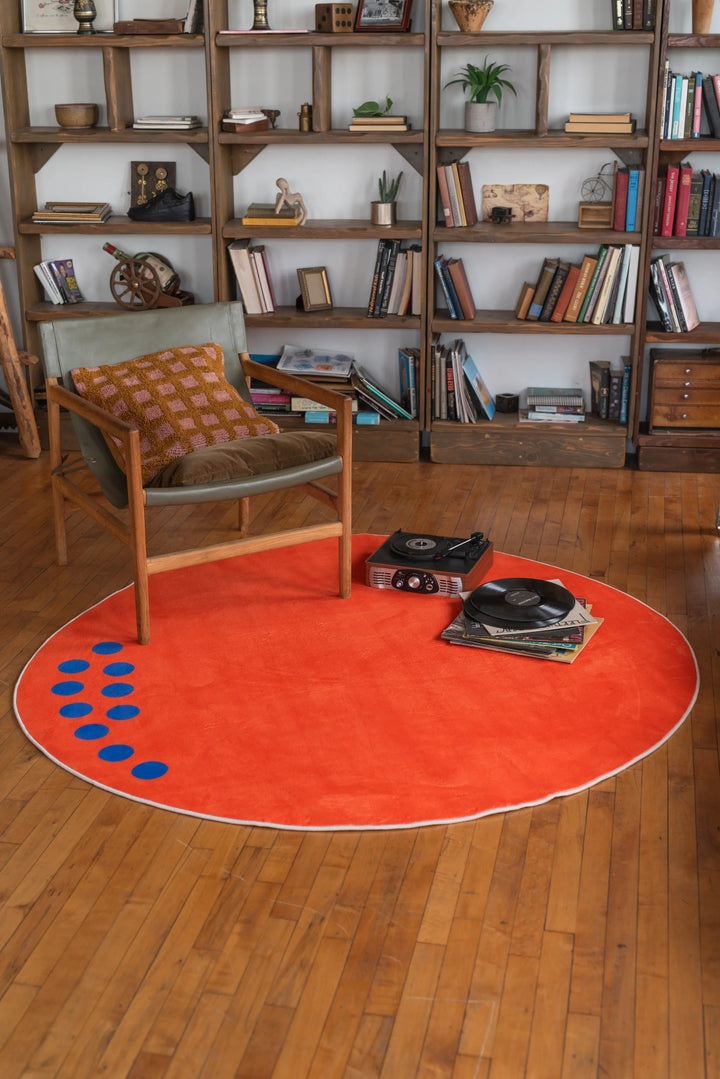 Orange Minimalist Rug by Becca Franks in living room, under wooden chair and vinyl records on floor