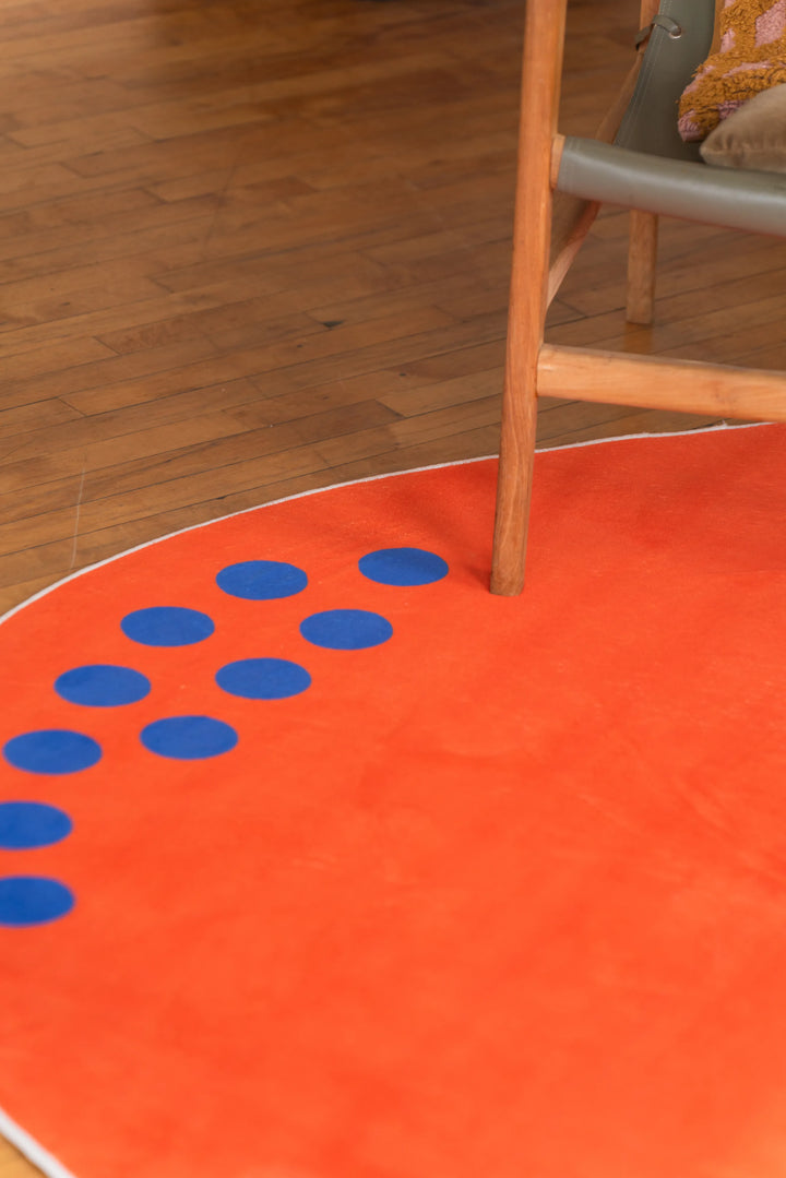 A wooden chair partially on an orange rug with a curved line of blue dots along the border
