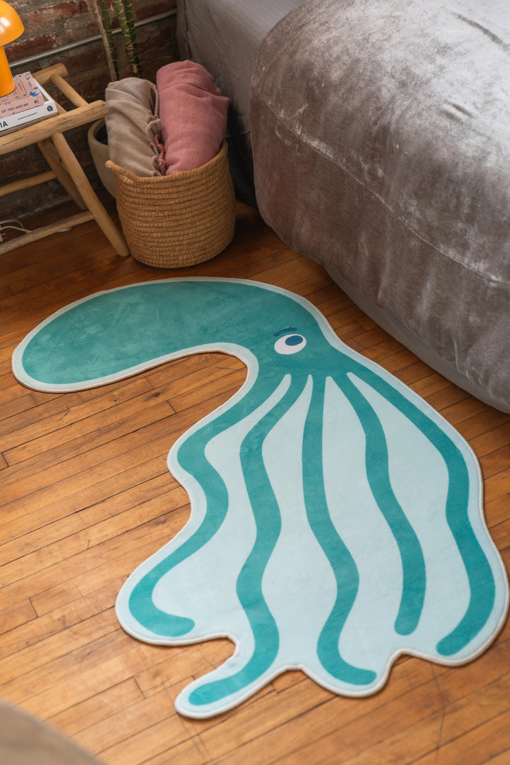 Irregular green area rug in octopus shape next to bed and woven basket in bedroom corner