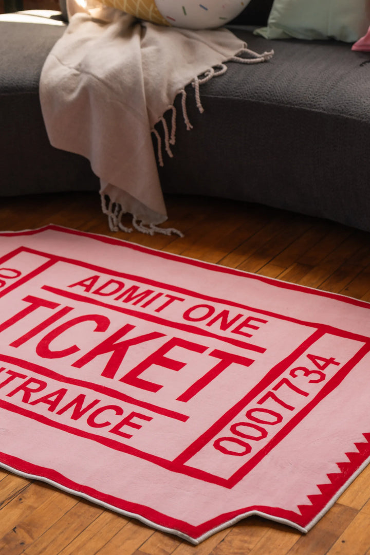 Close-up of red ticket-shaped rug on wood floor in front of dark gray curved sofa