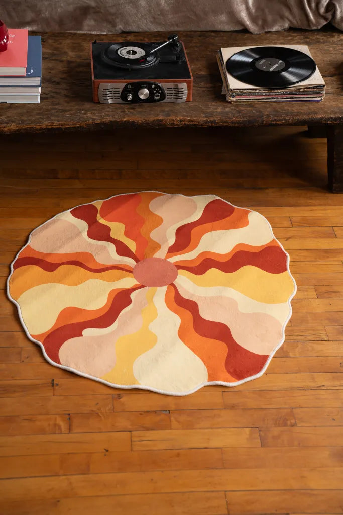 The sundial rug laid out near a rustic wooden table with records, styled in a retro-inspired bedroom.
