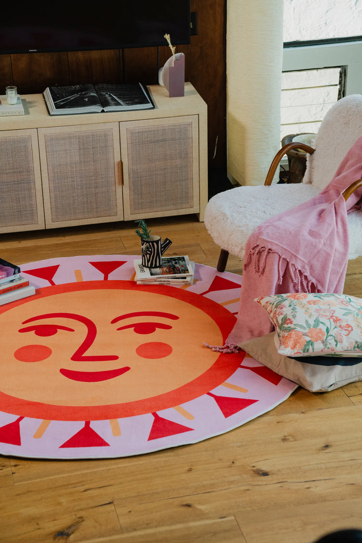 Sunburst round rug with peach and red tones styled near a boucle ...